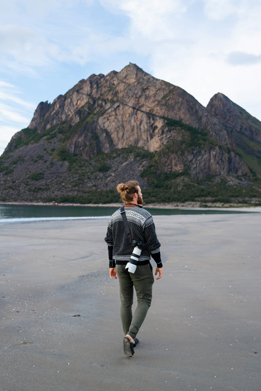 a person walking on a beach with a mountain in the background