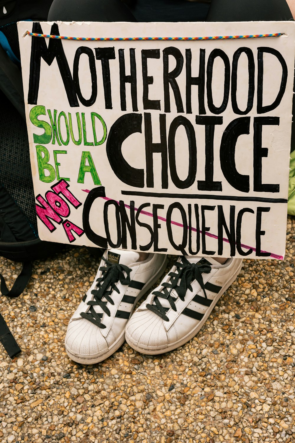 a person holding a sign that says motherhood should be a choice