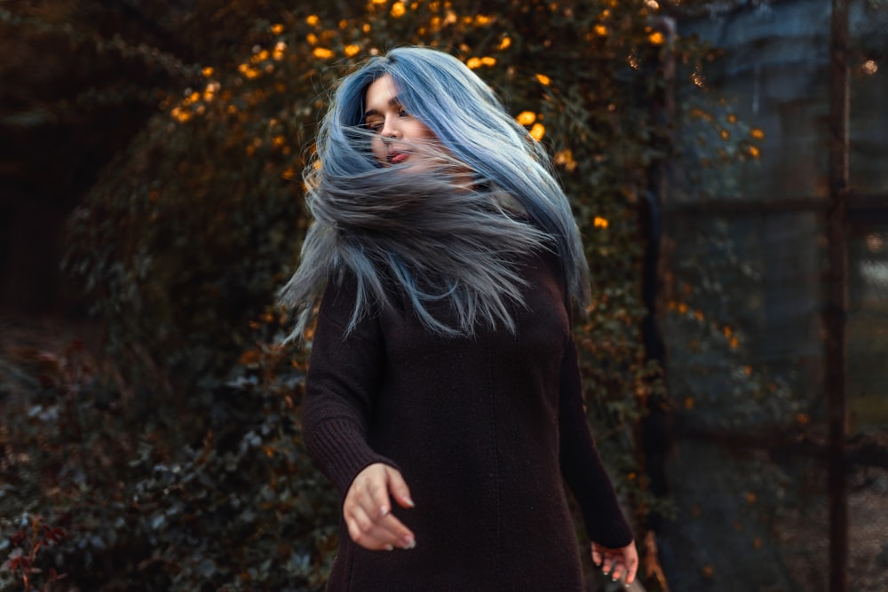 a woman with blue hair walking down a street