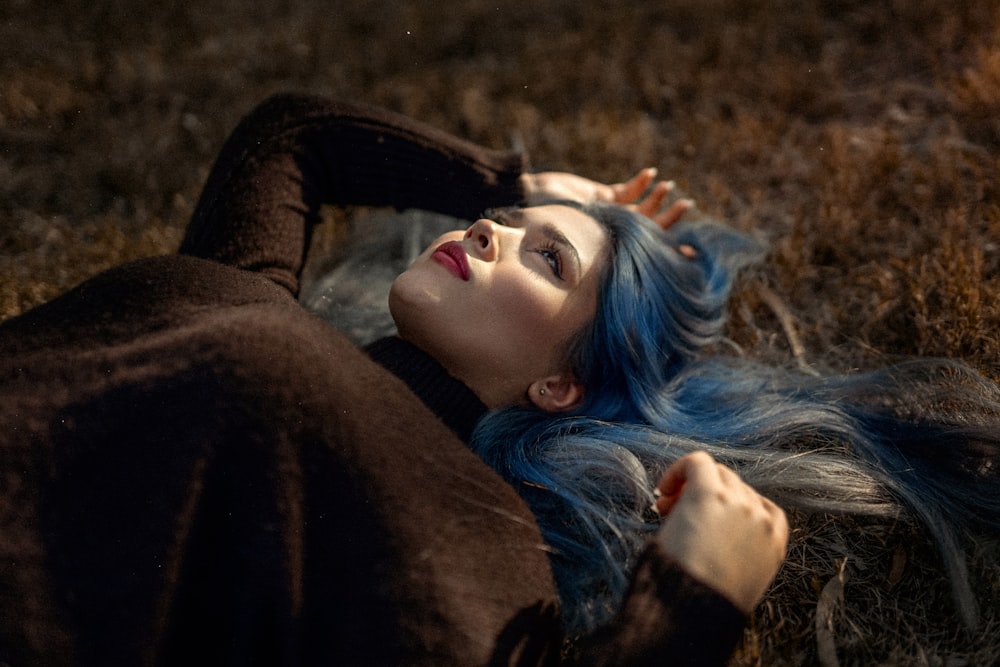 a woman with blue hair laying on the ground
