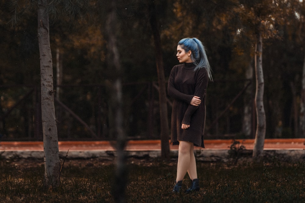 a woman with blue hair standing in a forest