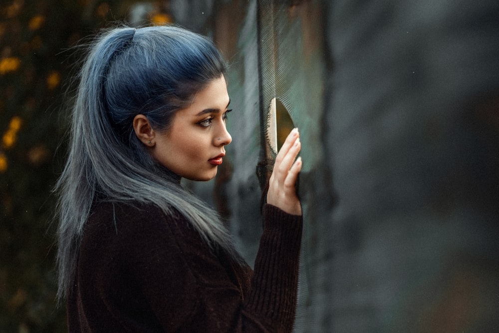 a woman with blue hair is holding a cell phone