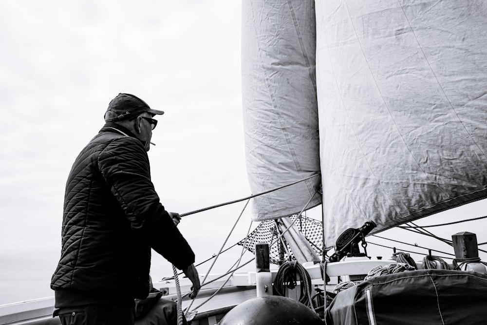 a black and white photo of a man on a sailboat