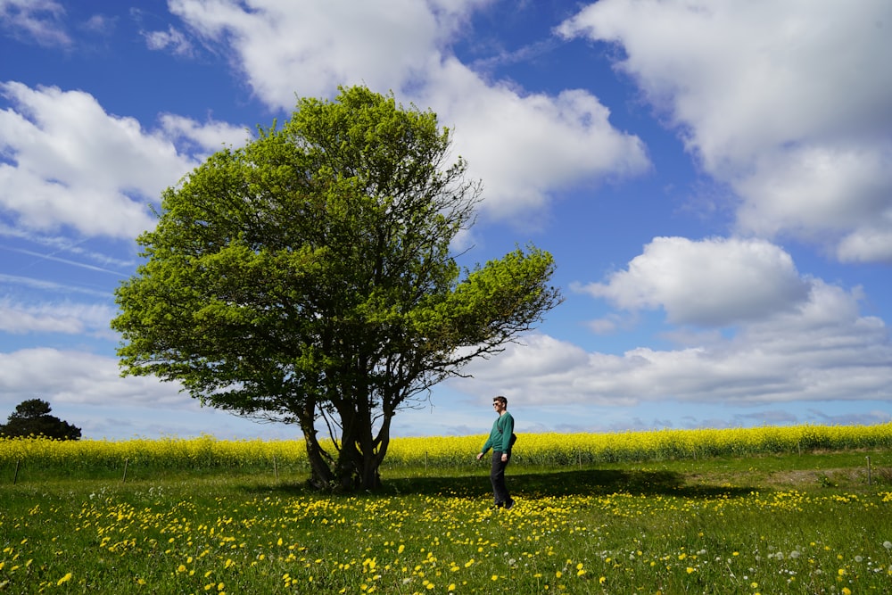 a man standing in a field next to a tree