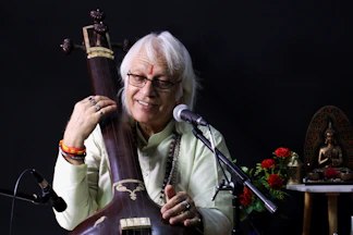 a man holding a musical instrument in front of a microphone