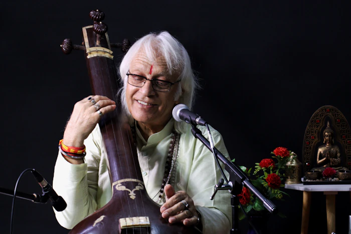 A musician holding a tanpura — a long-necked Indian drone instrument