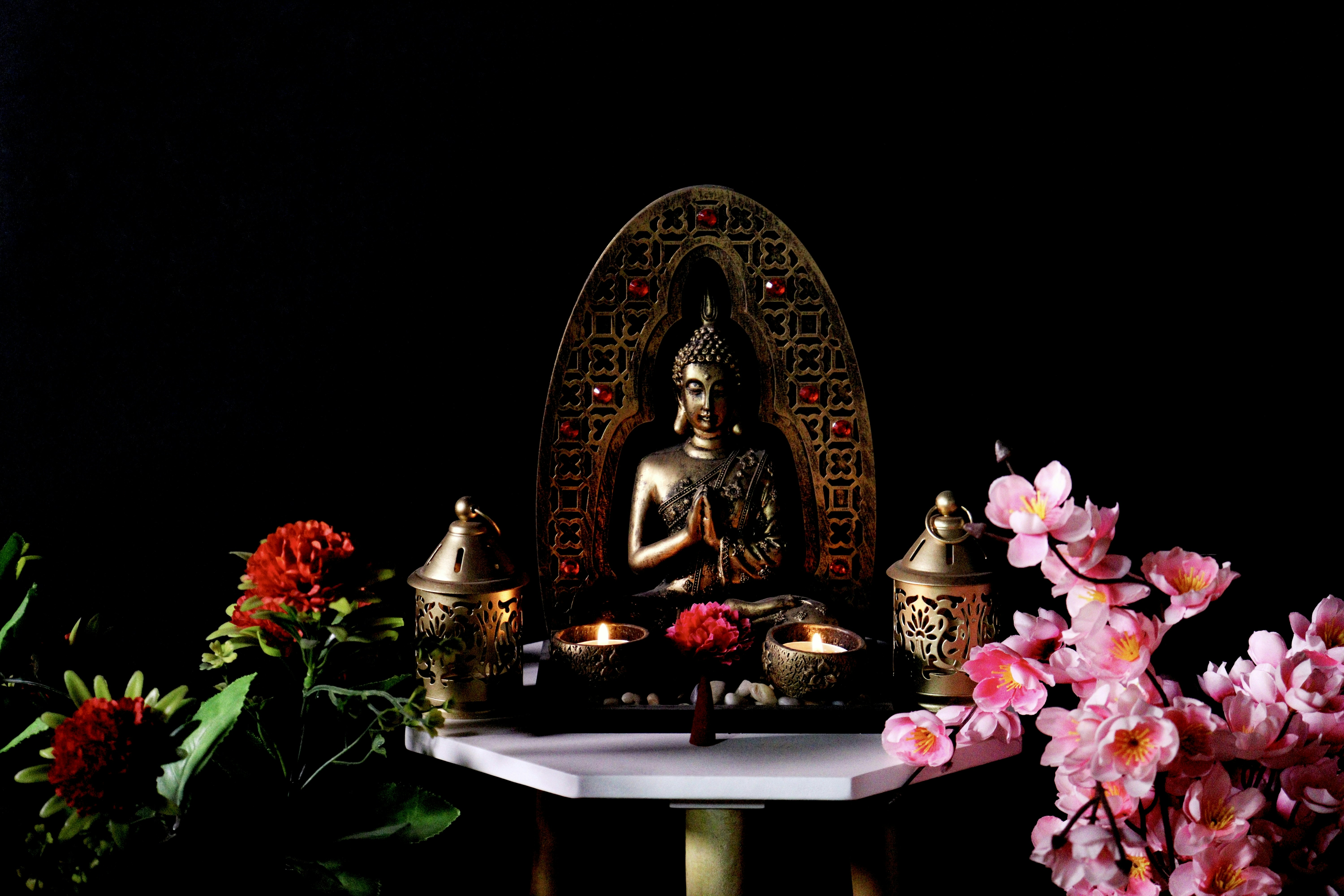 a buddha statue sitting on top of a table surrounded by flowers