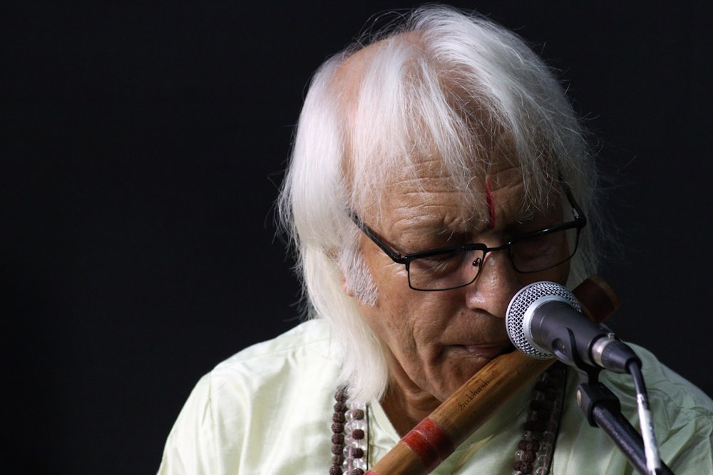 a man with white hair and glasses playing a flute