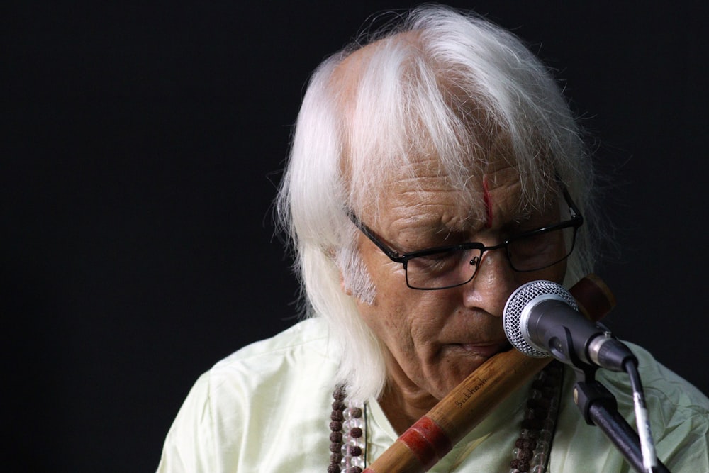 Un hombre con el pelo blanco y gafas tocando una flauta