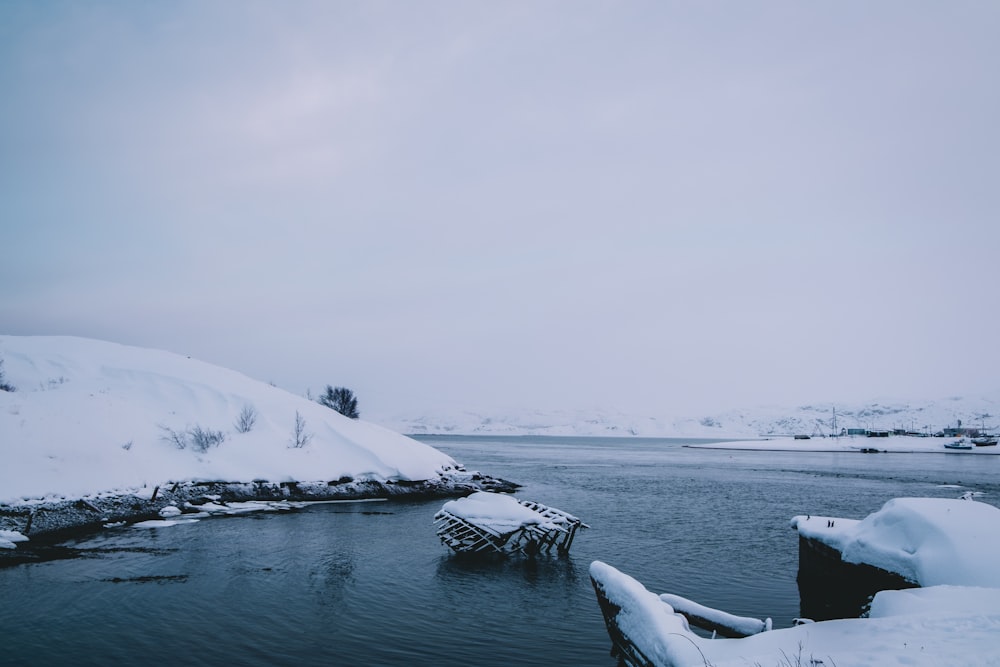 a body of water surrounded by snow covered hills