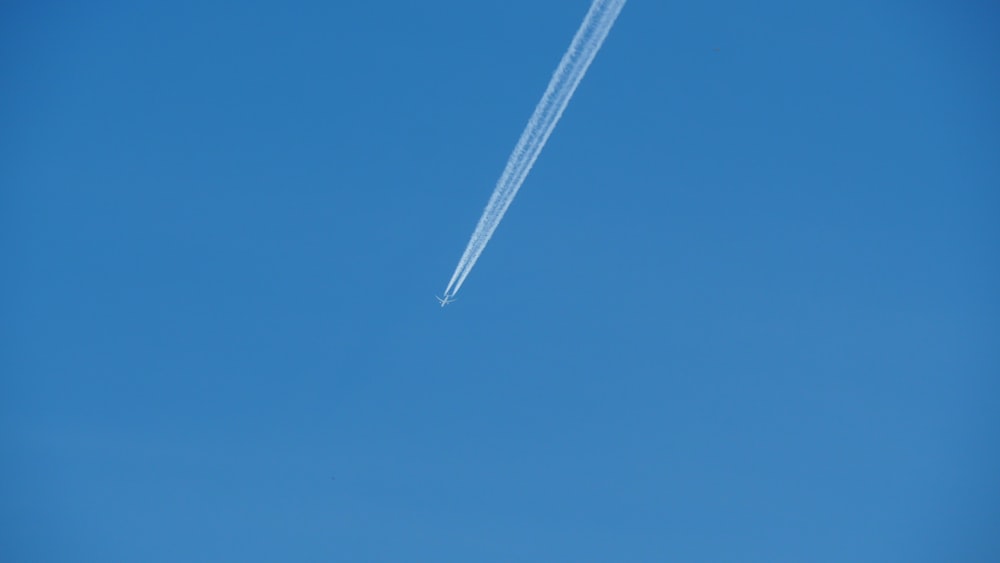 an airplane flying in the sky with a contrail