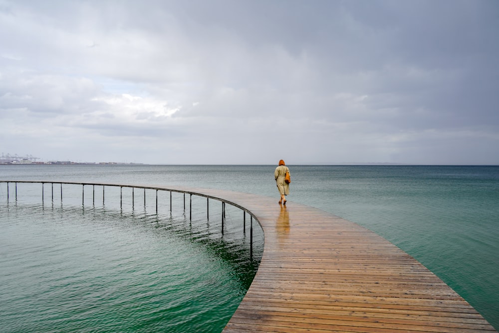 a person walking across a wooden bridge over a body of water