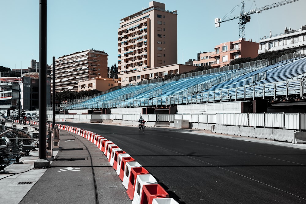 a man riding a motorcycle down a street next to a stadium