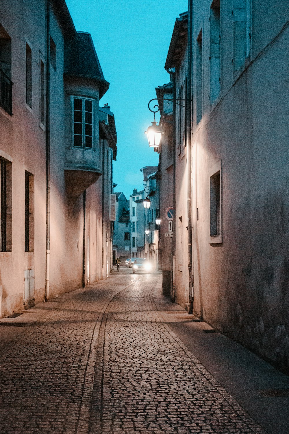 Eine Kopfsteinpflasterstraße bei Nacht mit eingeschalteter Straßenlaterne