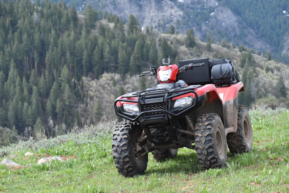 Un vehículo rojo de cuatro ruedas estacionado en una colina cubierta de hierba