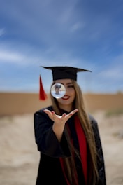 a woman in a graduation cap and gown holding a magnifying glass