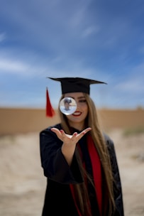 a woman in a graduation cap and gown holding a magnifying glass