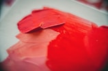 Detailed shot of textured brushstrokes on a bold red canvas.