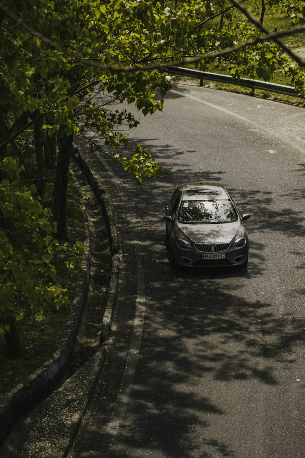 um carro está dirigindo por uma estrada arborizada