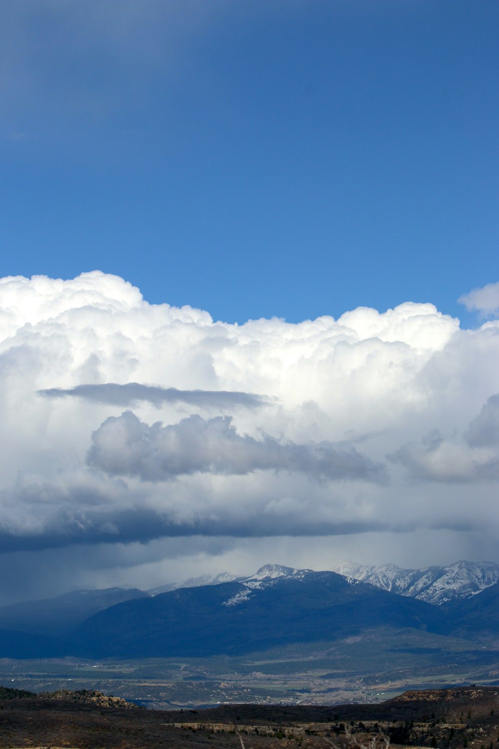 a mountain range under a cloudy sky with mountains in the distance