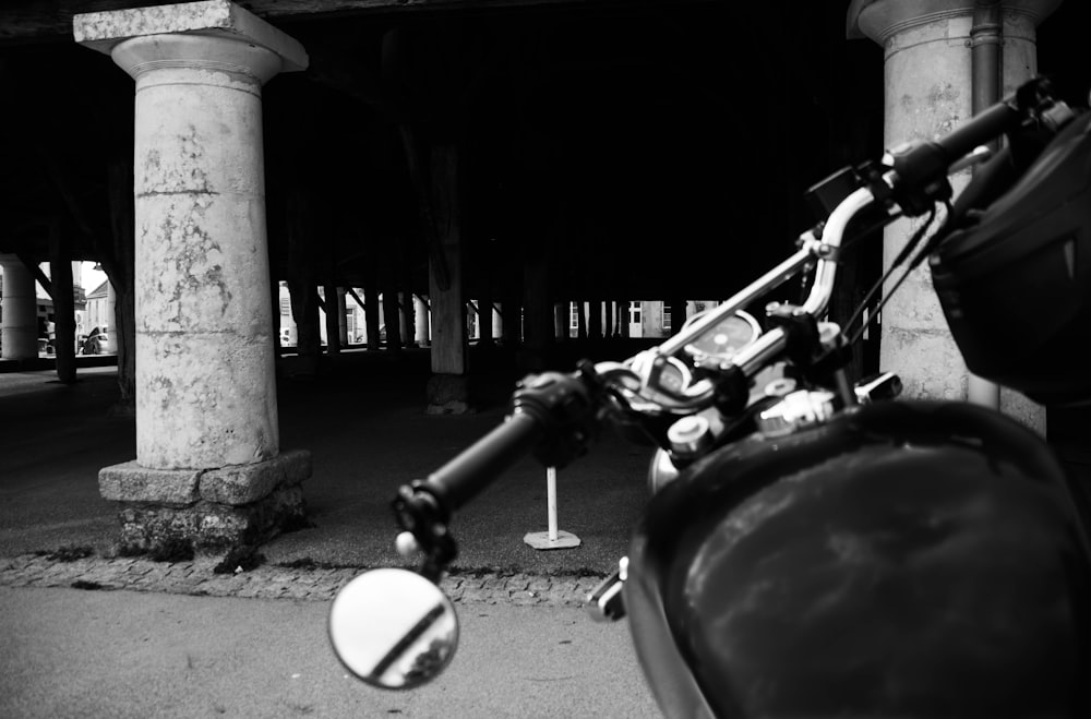a black and white photo of a motorcycle parked under a bridge