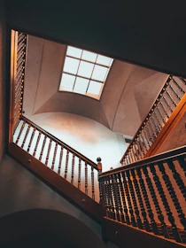 Interior view of a high-end residential stairwell with a double-height family room and natural light pouring through a large skylight.