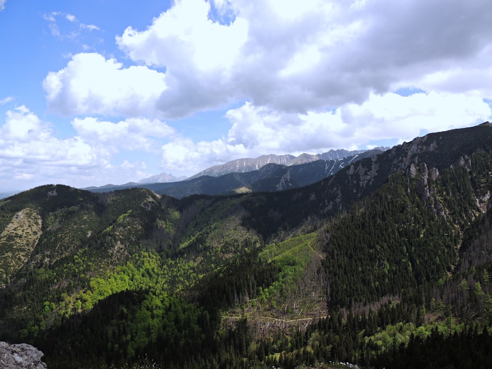 a scenic view of a mountain range with trees and mountains in the background