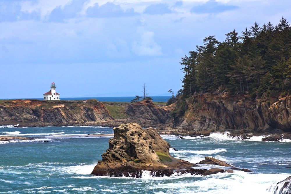 a lighthouse on top of a rocky outcropping near the ocean