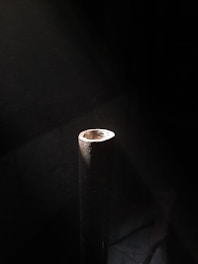 Close-up of a steel pipe with diameter 90mm resting on a wooden surface.