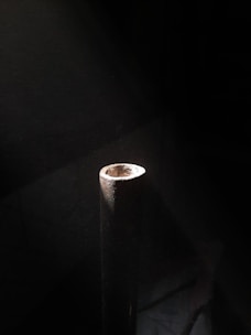 Close-up of a steel pipe with diameter 90mm resting on a wooden surface.