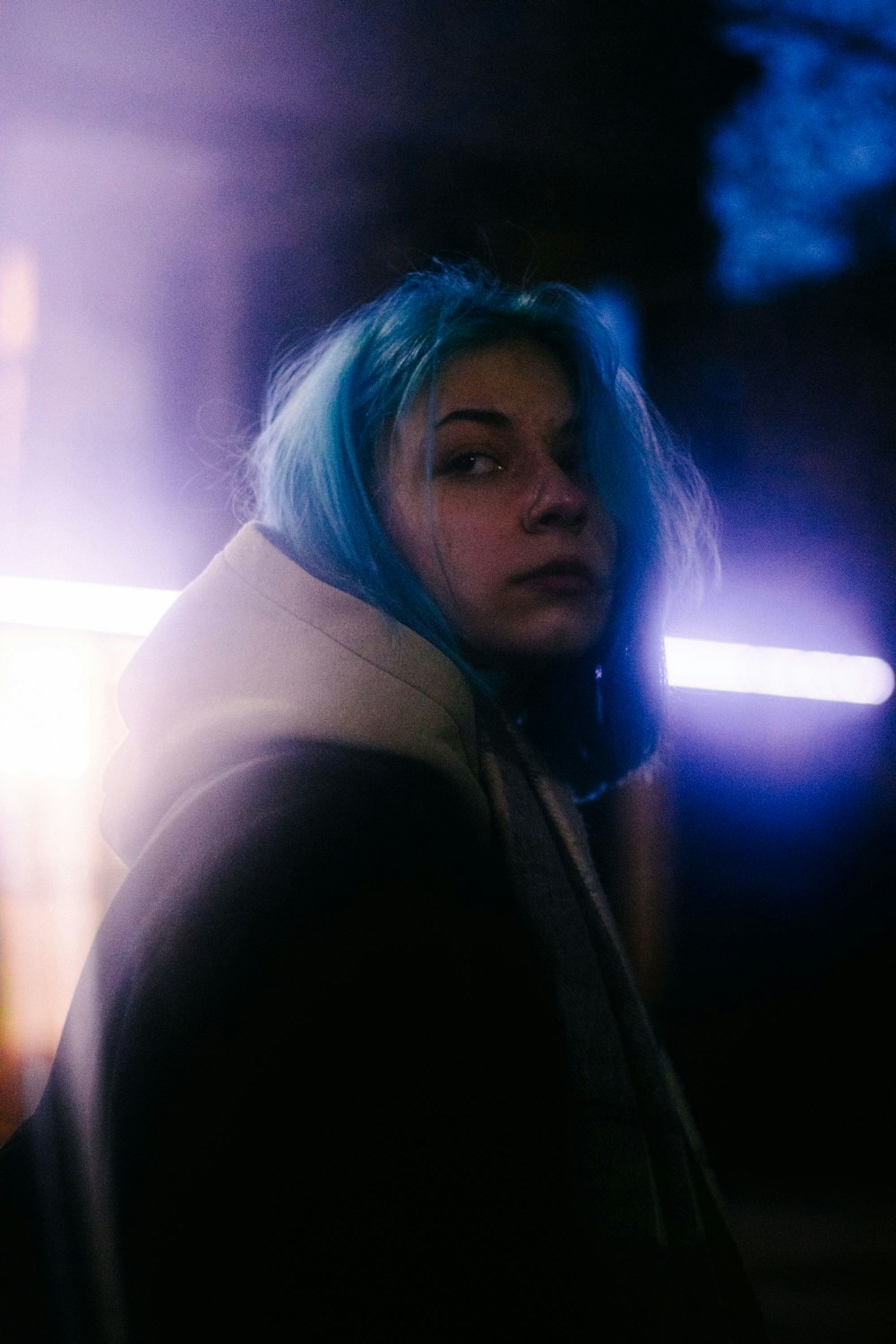 a woman with blue hair standing in a dark room