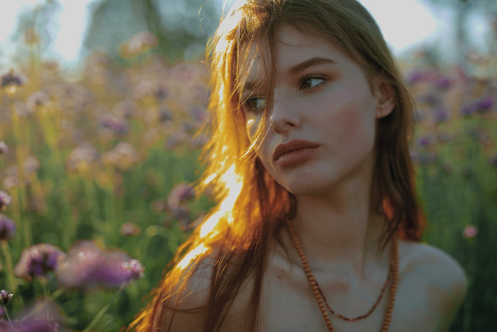 a beautiful young woman sitting in a field of flowers