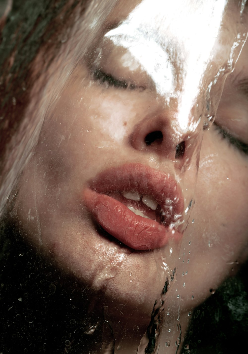 a close up of a woman's face under a shower of water