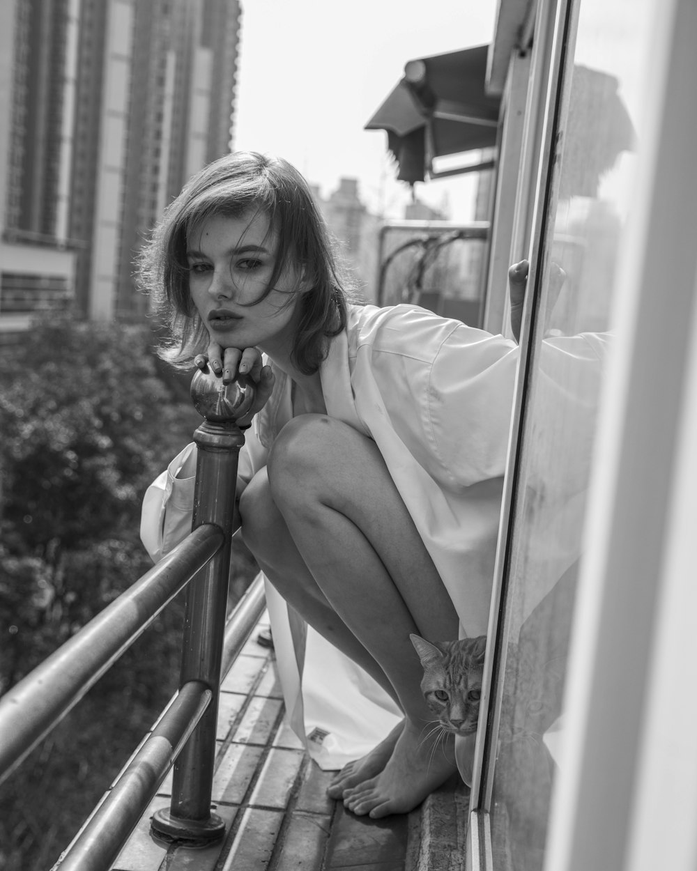 a black and white photo of a woman leaning on a rail