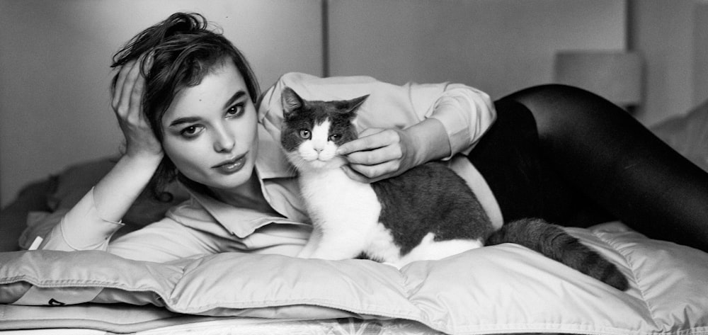 a woman laying on a bed with a cat