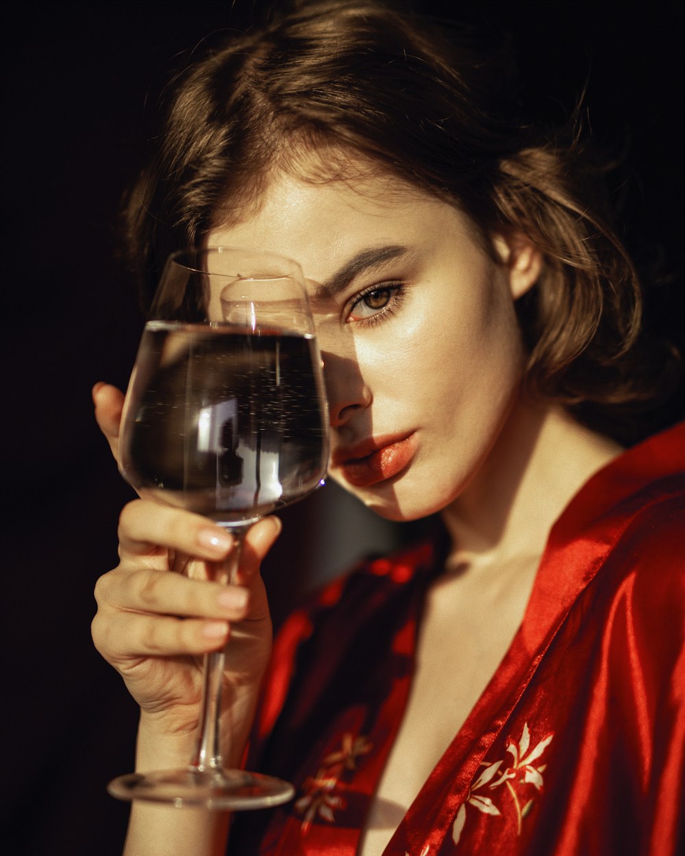 a woman in a red robe holding a glass of wine
