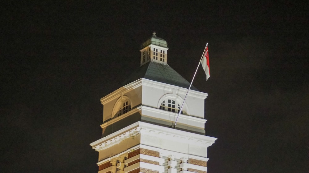 uma torre do relógio alta com uma bandeira em cima dela