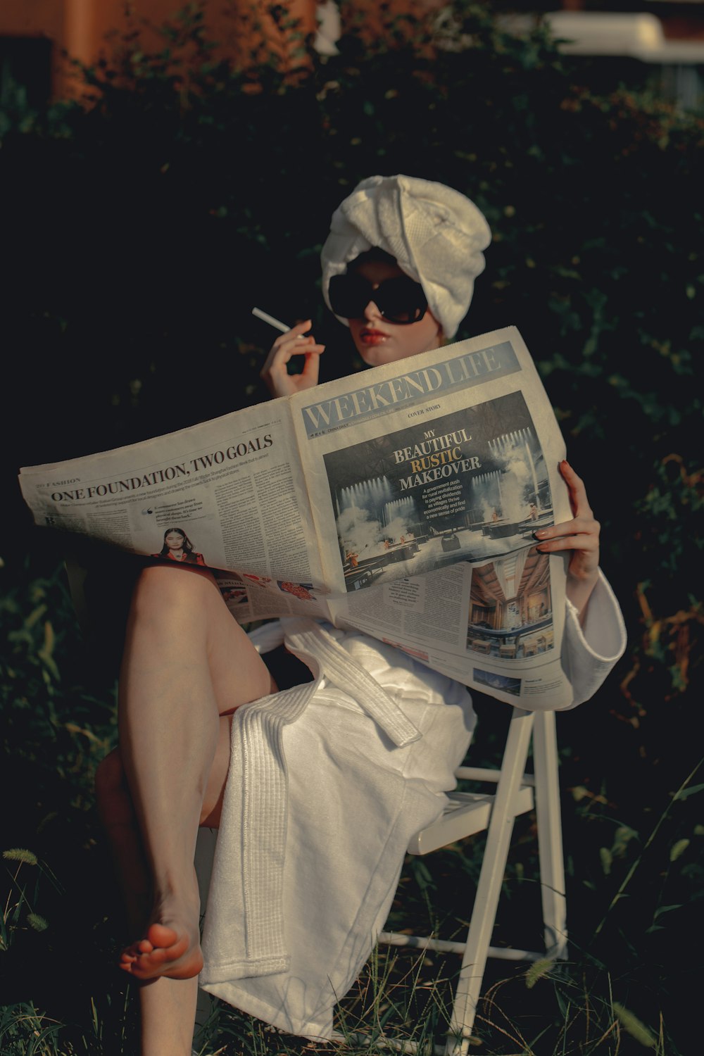 a woman sitting on a chair while reading a newspaper