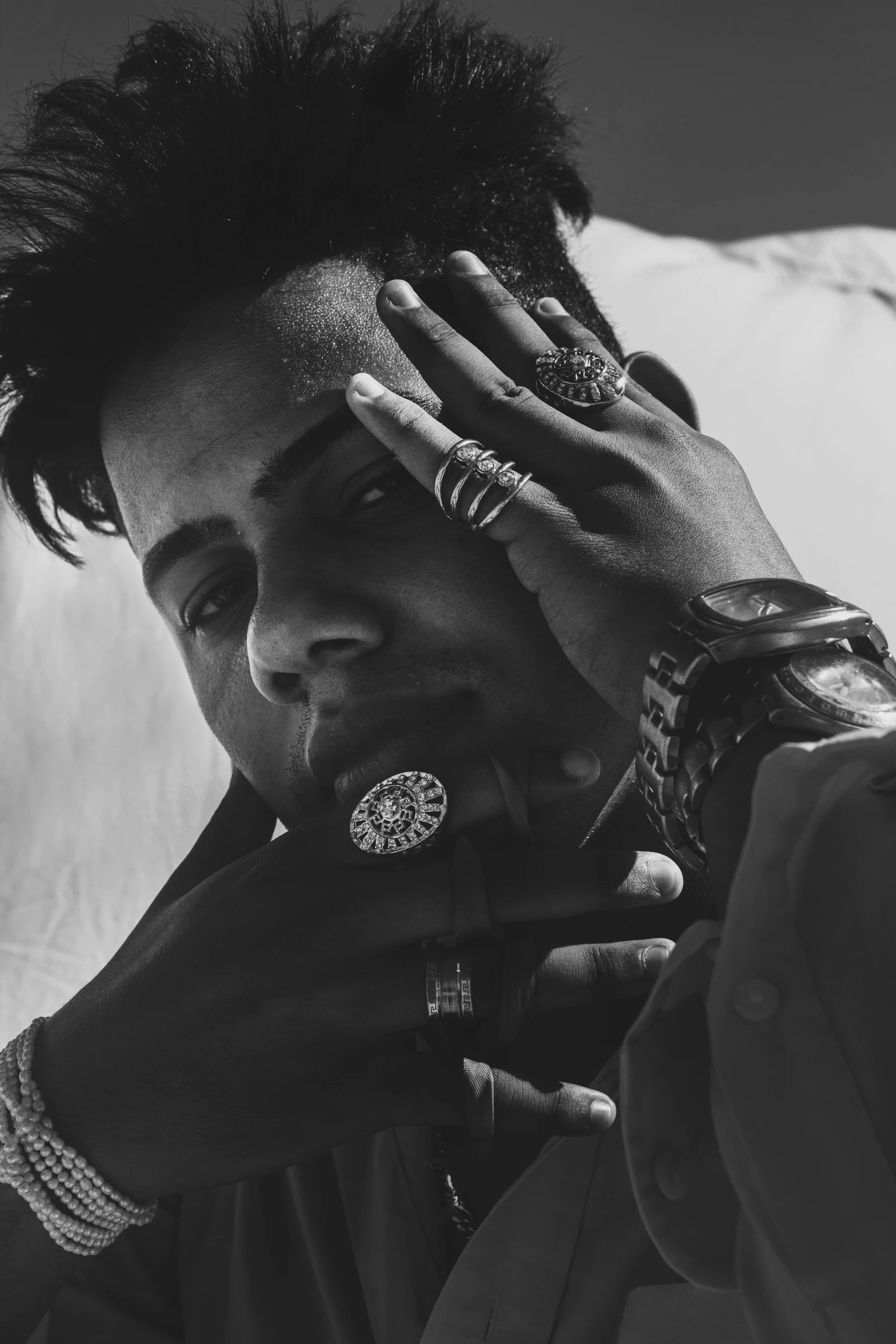 A stylish model wearing layered silver bracelets and rings, set against a muted urban backdrop that highlights the modern edge of the collection.
