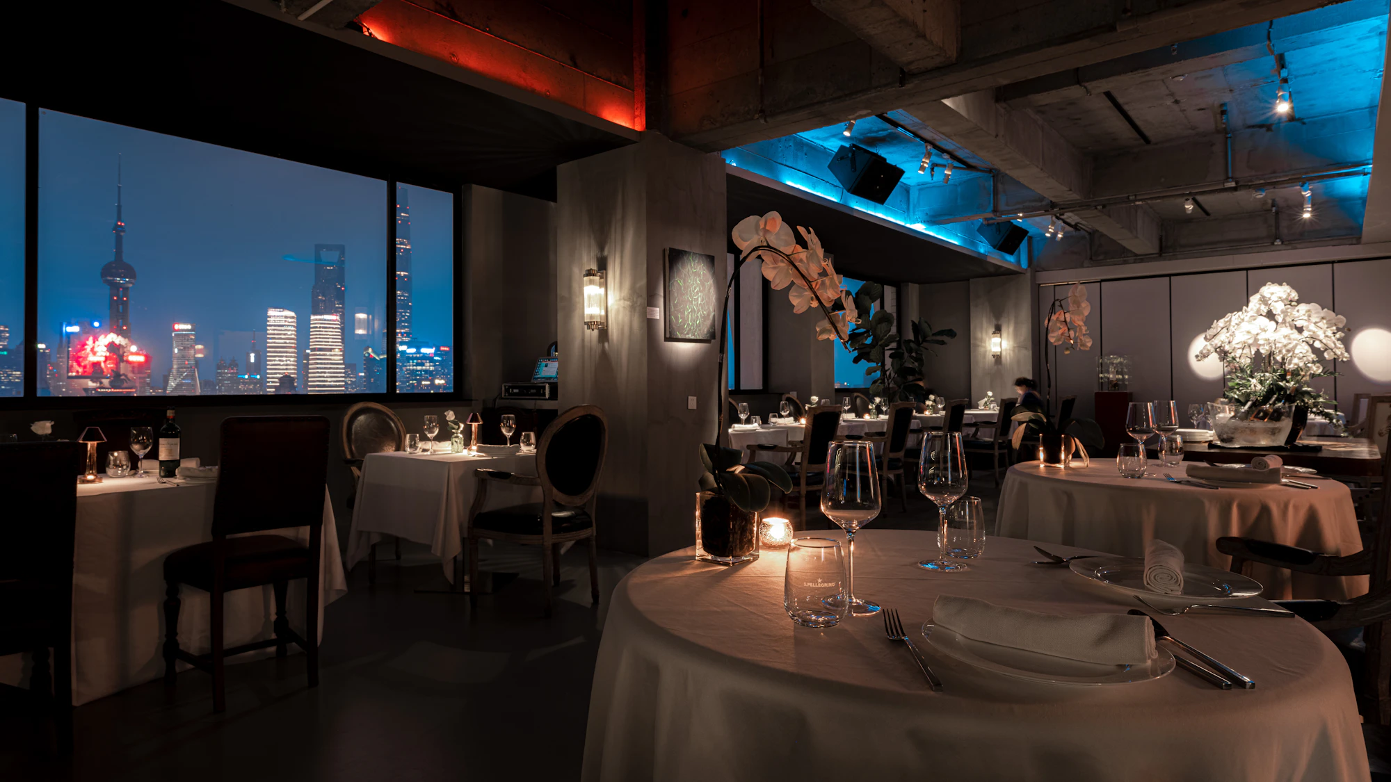 Dimly lit fine dining room with a view over the city at night