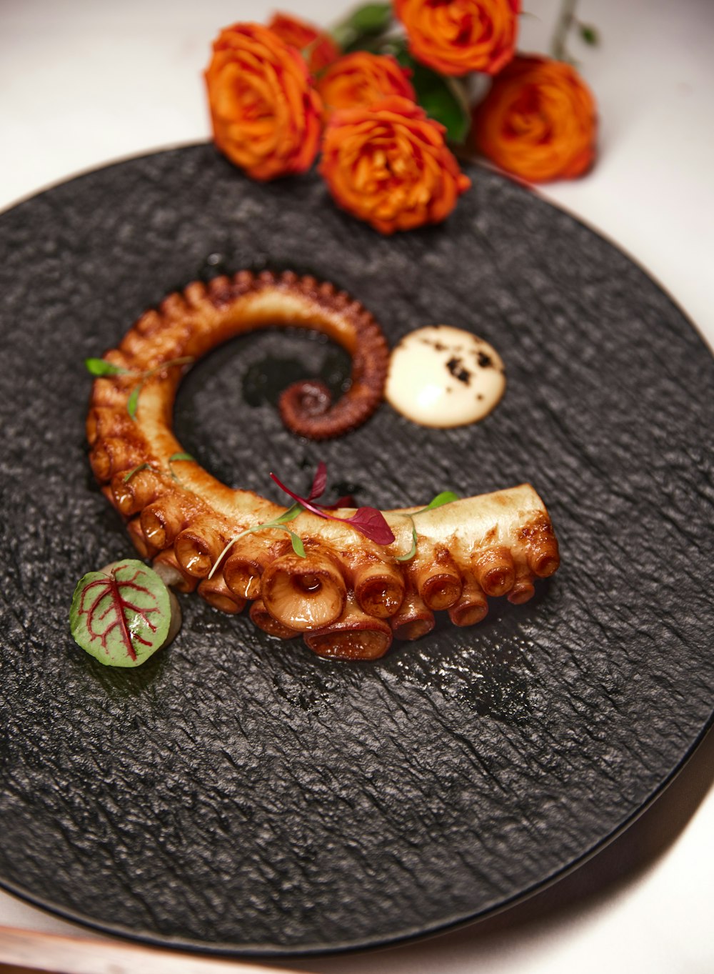 a black plate topped with an octopus and other food items
