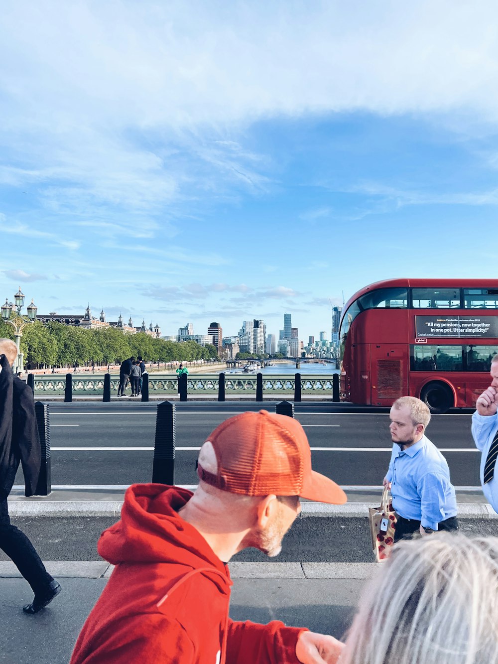 a group of people walking down a street next to a red double decker bus