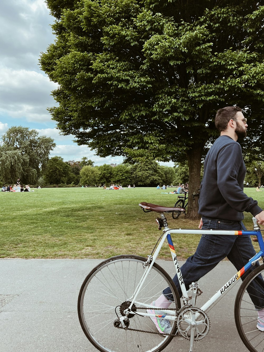 a man riding a bike down a street next to a park