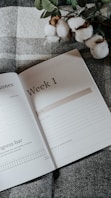 a book opened on top of a bed next to a plant