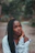 a woman with long braids sitting on a dirt road