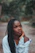 a woman with long braids sitting on a dirt road