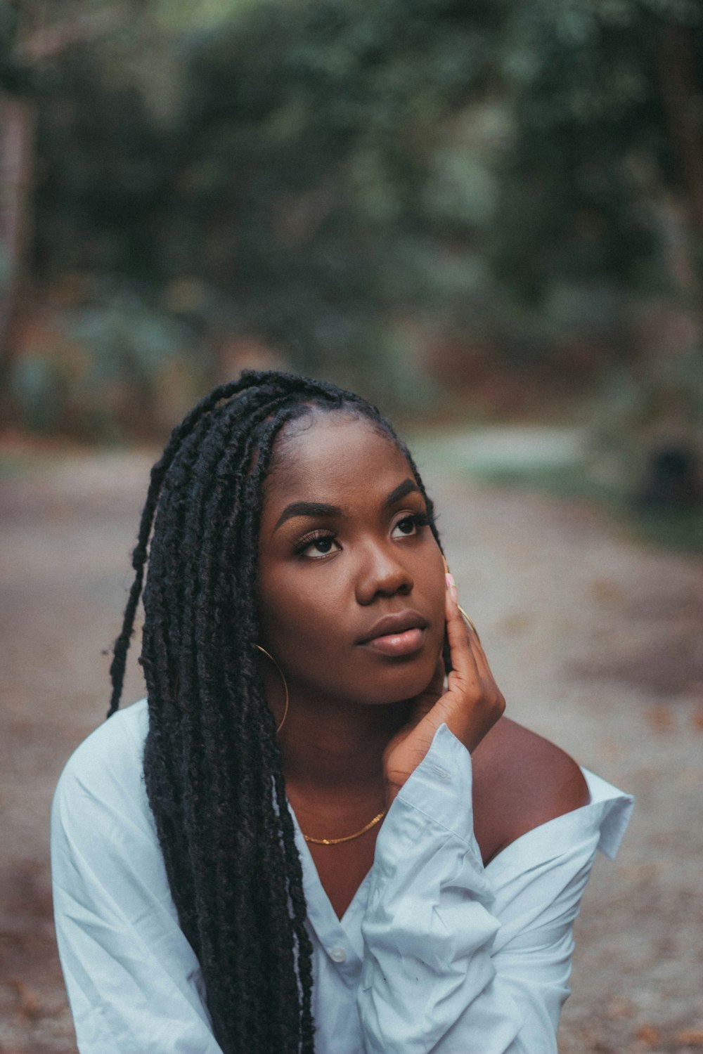 a woman with long braids sitting on a dirt road