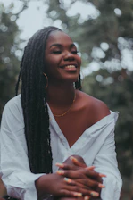 Smiling black female nurse with braids, wearing a stethoscope and gold earrings, radiating warmth and professionalism.