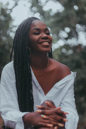 Smiling black female nurse with braids, wearing a stethoscope and gold earrings, radiating warmth and professionalism.