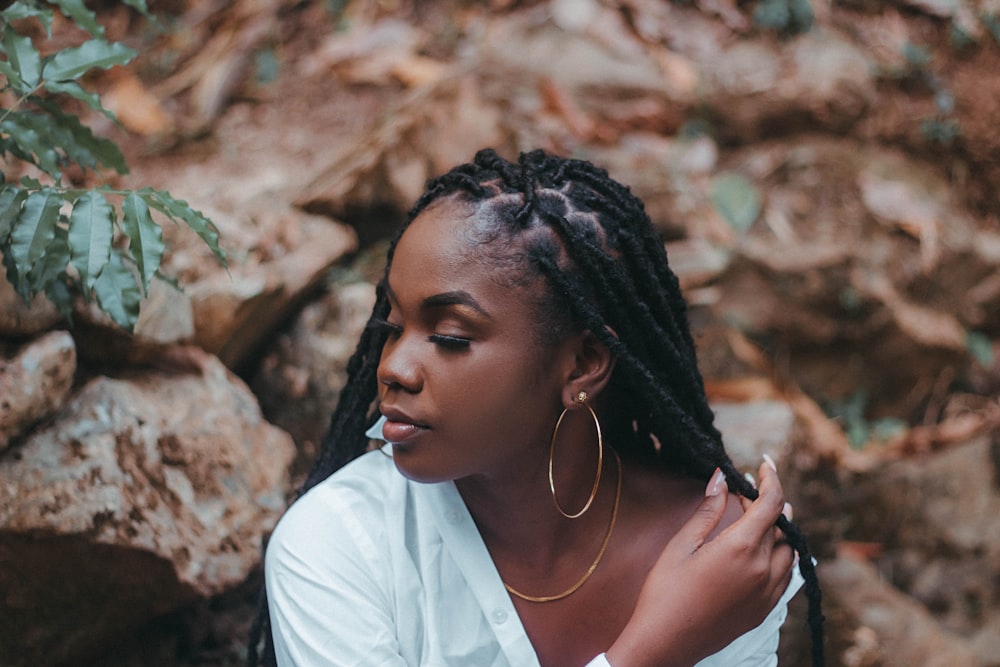 a woman with dreadlocks sitting in front of rocks